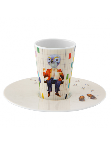 Tasse et soucoupe. On voit sur la tasse une créature habillé avec des carreaux de couleurs à côté